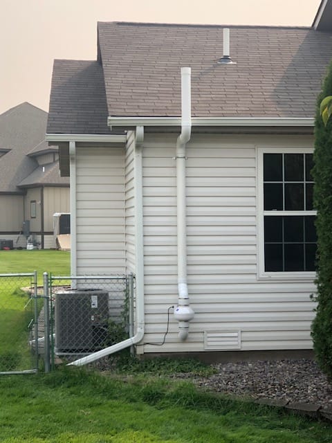 An original photo of a white radon mitigation system installed on a home by Murphy Radon.