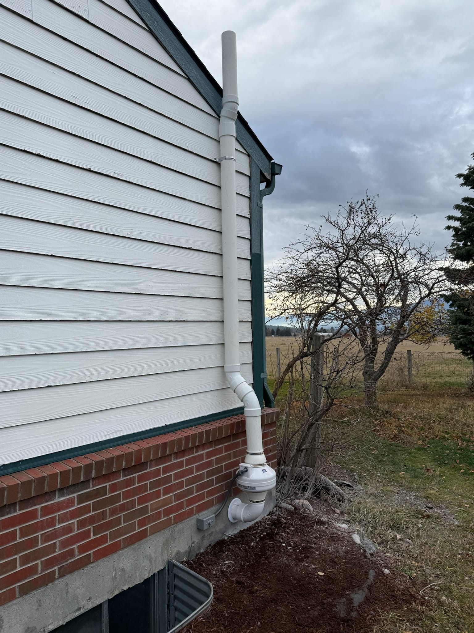 An original photo of a white radon mitigation system installed on a home by Murphy Radon.