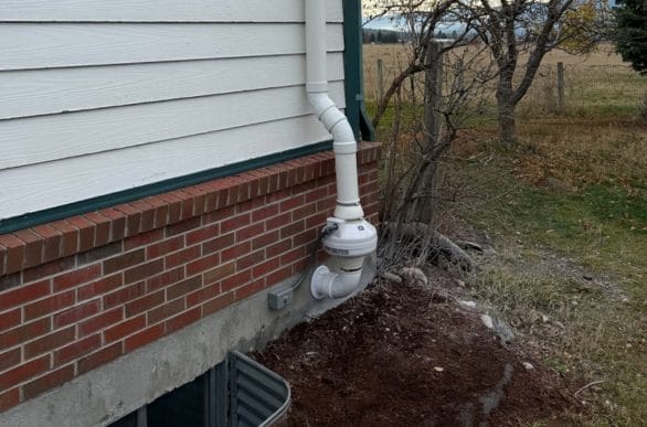 An original photo of a white radon mitigation system installed on a home by Murphy Radon.